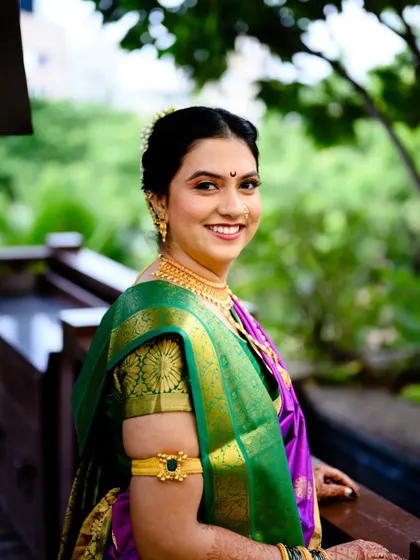 A beautiful portrait of the bride, Poorva, on her wedding day. Her smile is so warm, and the green and purple saree looks stunning against the natural backdrop.