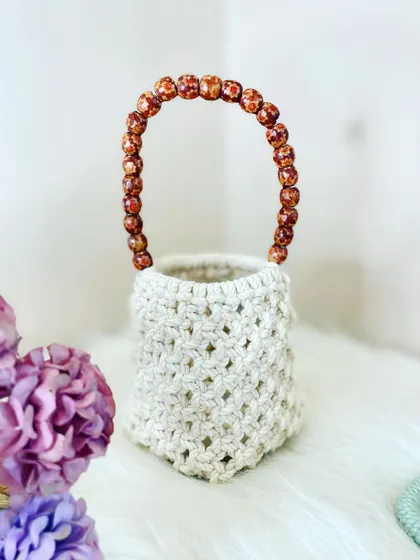 My macrame potli bag is a perfect accessory for festive occasions. This one is made with a natural cream cord and features a handle made of beautiful amber-colored beads.