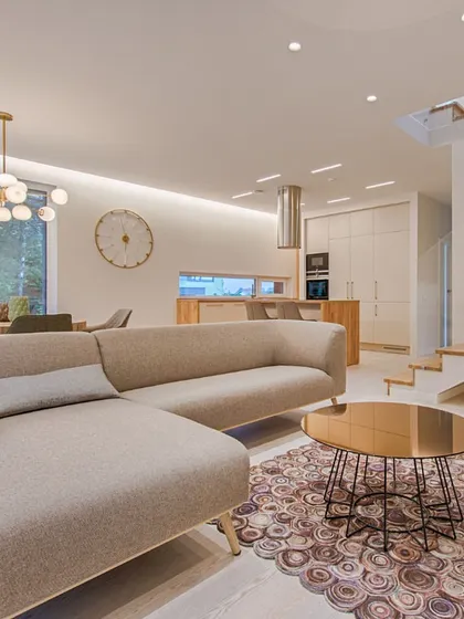 An example of a spacious, open-plan living area that combines the living room, dining space, and kitchen. The design uses a neutral color palette, modern furniture, and strategic lighting to create a sense of flow and sophistication.