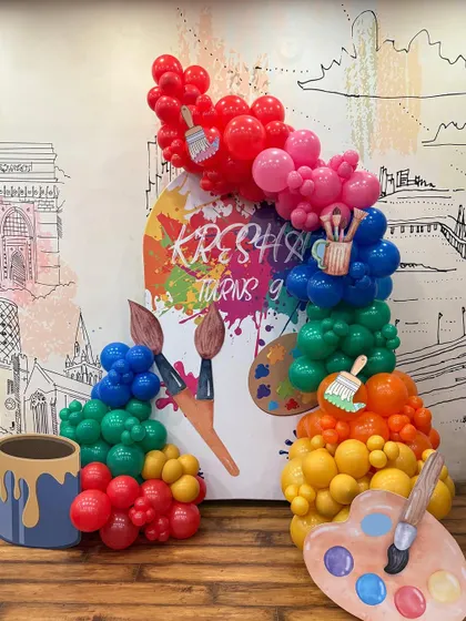 An art-themed birthday party for a creative 9-year-old. The decor is designed to look like a colorful paint palette, with balloon "paint spills" and brush cutouts.