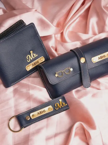 My custom men's daily essentials kit in a deep blue. This set, featuring a wallet, sunglasses case, and keychain, can be personalized with a name and your choice of over 100 charms.