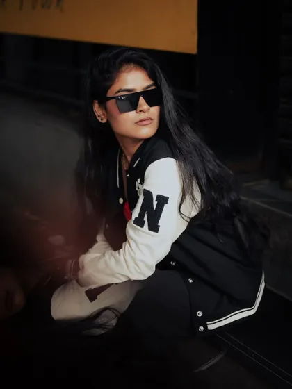 A low-light street portrait with a cool, edgy vibe. The shadows and the model's sunglasses create a mysterious and stylish look.