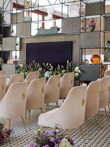 The indoor seating for the sustainable engagement, featuring subdued suede pastel chairs and pockets of floral gardens. The backdrop was intricately woven by hand by women artisans.