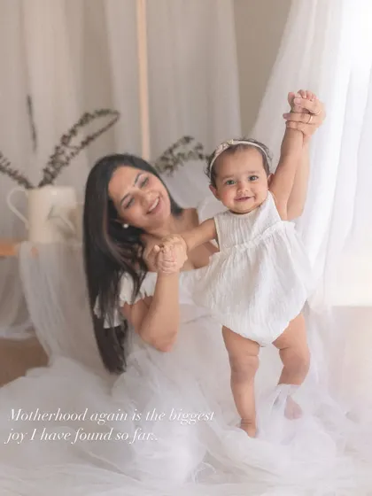 "Motherhood again is the biggest joy." A mother helps her baby take her first steps, a milestone moment filled with happiness and pride.