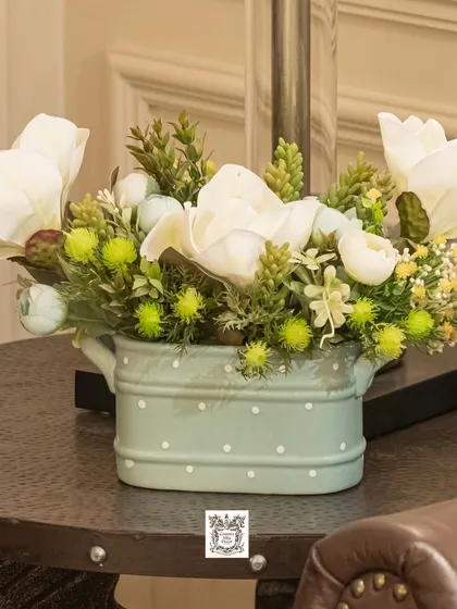 A closer look at the mint green pot with white artificial flowers, showcasing its charming and rustic appeal. It's a small detail that can brighten any corner.