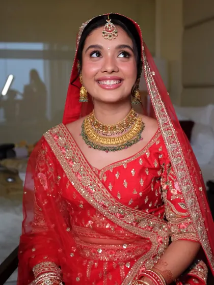 Looking up with a happy, dreamy expression. This photo shows how a minimal, glossy makeup look can make a bride in a traditional red outfit look absolutely radiant.