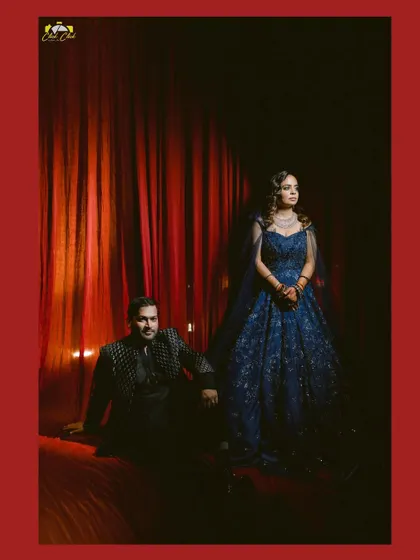A regal portrait of the couple against the rich, red backdrop of their sangeet decor.