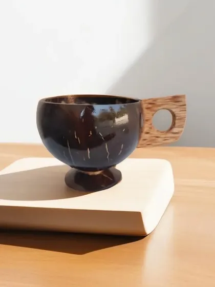 This unique mug is crafted from a polished coconut shell with a wooden handle. It is 100% natural and safe for hot beverages like tea and coffee, offering a truly unique and sustainable drinking experience.