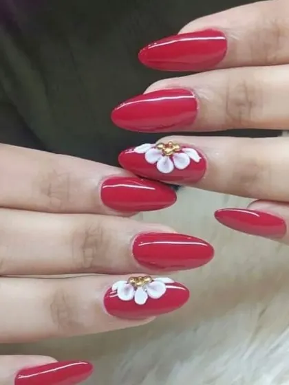 A simple yet elegant design with classic red nails and a single 3D white flower on each hand.