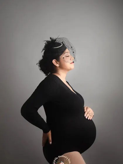 Sometimes, a simple and classic portrait is the most powerful. Using a minimalist backdrop and a simple black bodysuit, we can create a striking image that focuses entirely on the beautiful silhouette of your pregnancy. It's modern, artistic, and timeless.