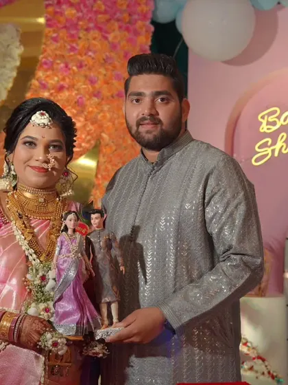 A happy couple at their baby shower, holding the custom dolls we made to replicate their outfits. It's a wonderful keepsake to remember their special day.