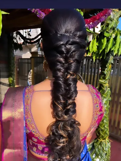 A fishtail braid on highlighted hair, ending in soft curls for a modern and textured finish.