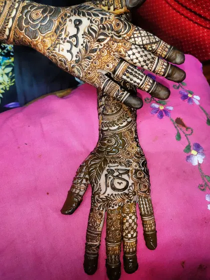 A close-up of the palms, showing the detailed figures and symbols incorporated into this custom bridal henna.