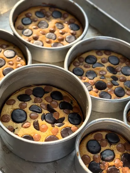 A fresh batch of our signature butter cakes, straight out of the oven. You can see the pools of melted Belgian chocolate in each one.
