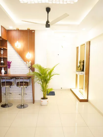 A wide view of the living area, showcasing the breakfast bar on the left and a serene Buddha corner on the right. The space is designed to be both social and peaceful.