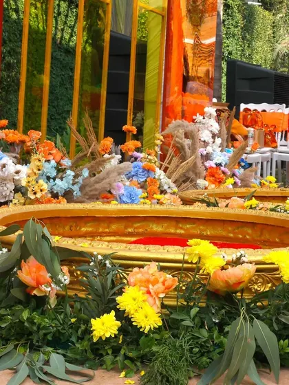 The Haldi seating area, with golden urlis surrounded by a profusion of colorful flowers. The mix of traditional elements with a modern color palette creates a fresh and beautiful look.