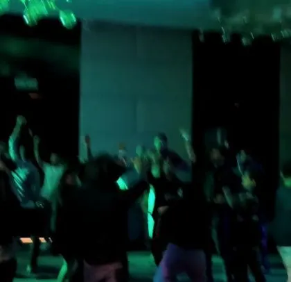 A dark, club-like atmosphere created with minimal lighting and a bright LED screen.