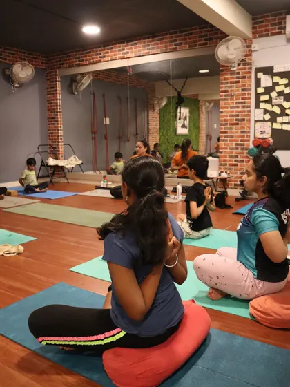 Students use cushions to sit comfortably in Paschima Namaskarasana (Reverse Prayer Pose), which helps open up the shoulders and chest.