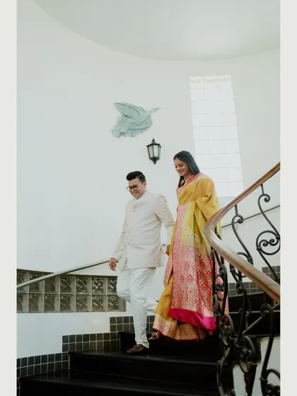 A full-view shot of the couple walking down a grand staircase, showcasing the architecture and their elegant attire. This creates a sense of grandeur for their engagement photos.
