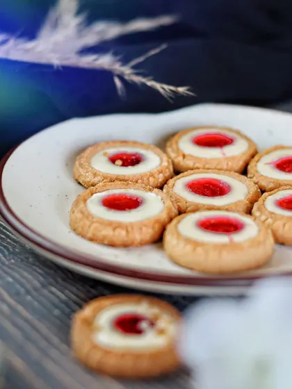 A plate of jam-filled cookies with a shallow depth of field. This angle gives a sense of abundance and makes you feel like you're right there, about to pick one up.