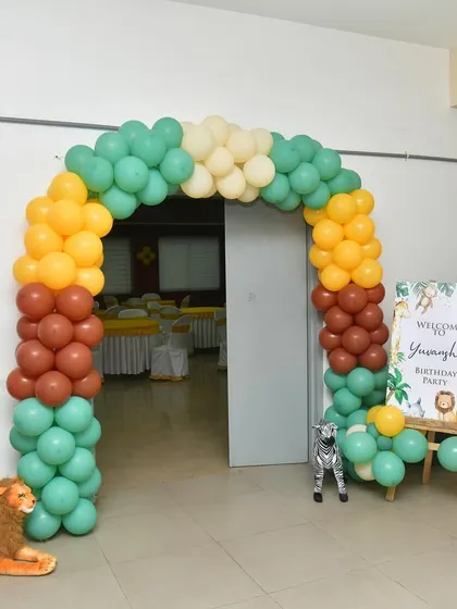 A simple and sweet jungle-themed entrance, this setup includes a colorful balloon arch and a personalized welcome sign. A plush lion toy adds a cute touch at the base.