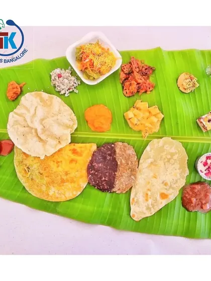 **A Feast for the Eyes:** This is what our full meal looks like on the traditional baale ele (banana leaf). This plate features our special "50-50 Holige", half classic and half chocolate, alongside a variety of authentic South Indian dishes.