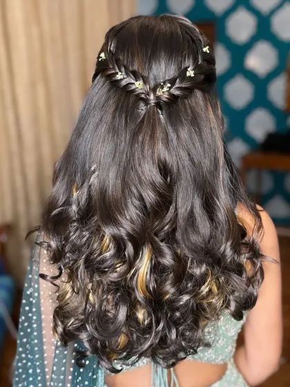 A romantic half-up hairstyle with a delicate braid and soft curls for Ruthvika's reception. This look is perfect for showing off long hair while keeping it neatly styled.