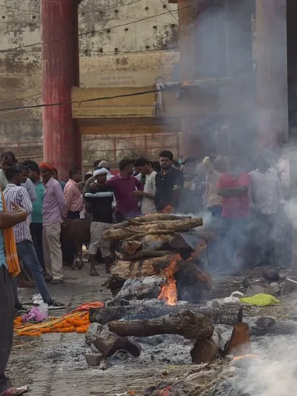 A cremation pyre burns at the ghats of Banaras. My documentary approach is to observe these sacred rites without intrusion, focusing on the environment and the collective gathering.
