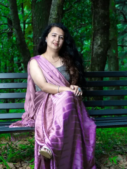 An elegant portrait of the bride-to-be sitting on a park bench. The beautiful purple saree and serene expression make for a timeless photo.