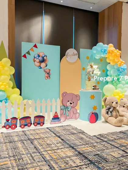 Another angle of the "Kayden" first birthday setup, showing the arrangement of the backdrops, the picket fence, and props like a toy train and stacking rings.