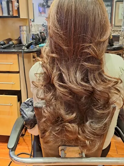 This angle shows the beautiful cascade of layers and curls from the back. This is a timeless salon blowout style.