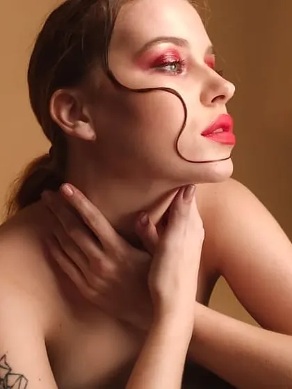 Another angle of the creative beauty look with red eyeshadow and a bold lip. This shot highlights the clean lines and precise application required for high-impact editorial makeup.