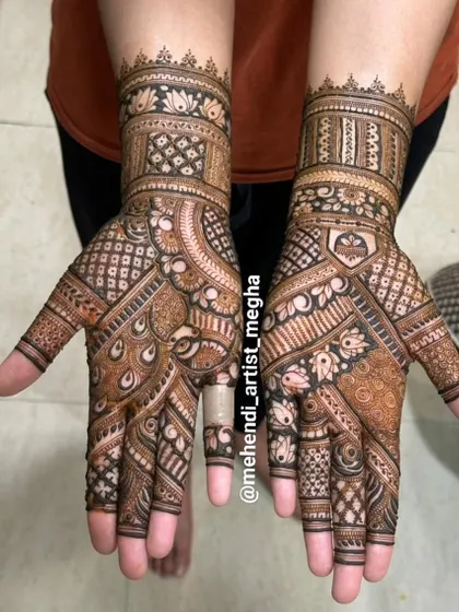 This design is packed with detail, featuring peacock feather patterns, checkerboards, and floral bands. It's a great example of a full, dense mehendi look.