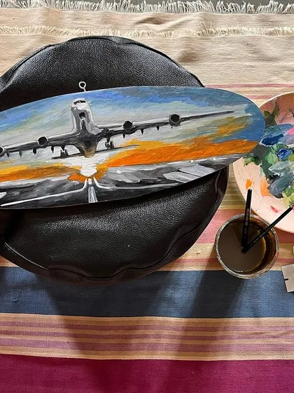 A top-down view of the completed airplane artwork on wood, next to my paint palette.