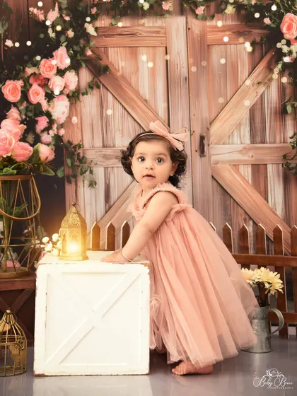 Taking her first steps into being one year old. This candid shot from a rustic floral-themed session captures a precious milestone.