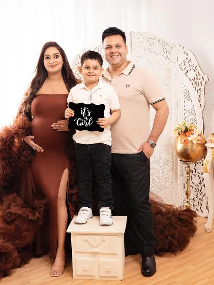 The whole family together for a maternity announcement. The big brother proudly holds the "It's a Girl" sign, making for a memorable family portrait.