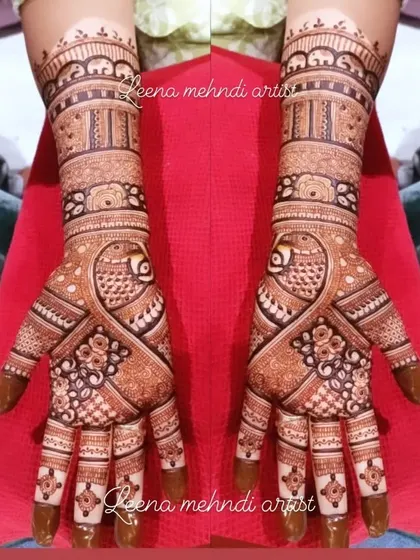 A classic bridal design featuring prominent peacock figures. The pattern uses a mix of delicate lines and bold shapes to create a balanced and eye-catching look that extends up the arm.