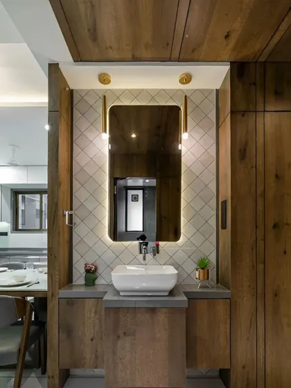 This wash basin area is located just off a dining space. I used a back-lit mirror and warm wood paneling to create a small but stylish feature that complements the home's overall design.