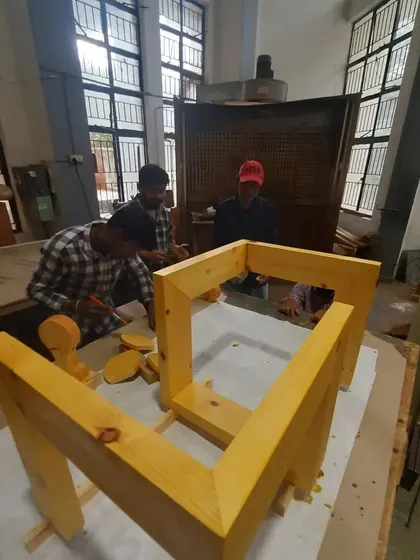 Students work on the intricate assembly of a modern table base, a project that tests their understanding of angles and joinery.
