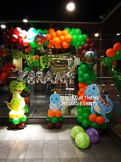 A vibrant dinosaur-themed balloon entrance with character cutouts and foil name balloons for Zaraah's party.