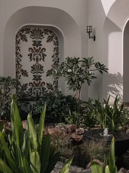 The water court at Rehethaan, featuring a lush green garden and a beautiful mosaic mural, creating a tranquil view from the entrance foyer.