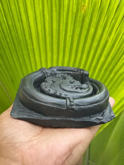 A small, circular vine with a bloom, handcrafted from Krishna shila stone, inspired by the intricate patterns found on temple walls.