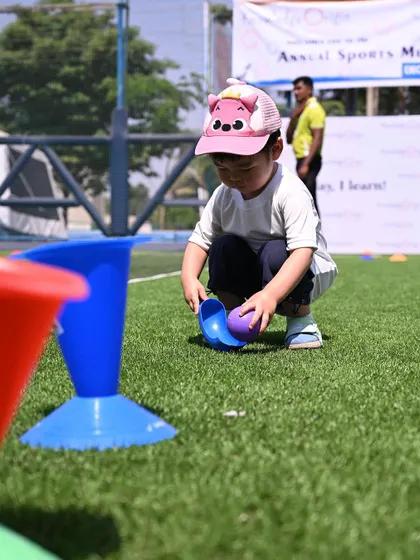 A toddler carefully places a ball into a cone, showing his developing hand-eye coordination.