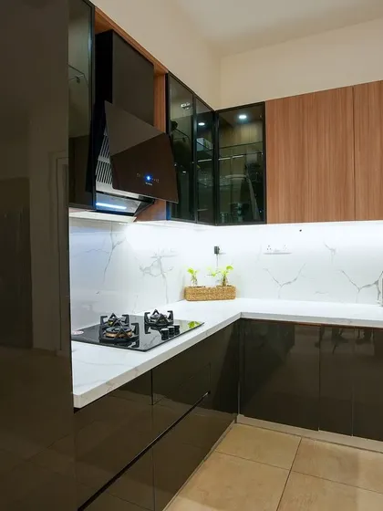 A close-up of the kitchen, highlighting the mix of glossy black and wood-finish cabinets, a white marble-veined backsplash, and efficient under-cabinet lighting.