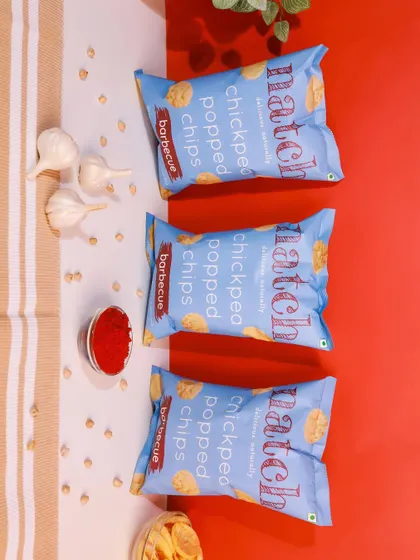 A top-down shot of barbecue flavored chips with ingredients like garlic and chili powder. The red and white background provides a nice contrast.