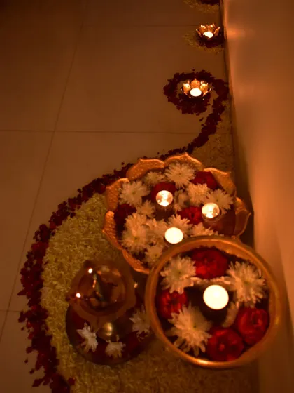 A close-up of the flower and diya arrangement. The colors and the soft light are just beautiful.