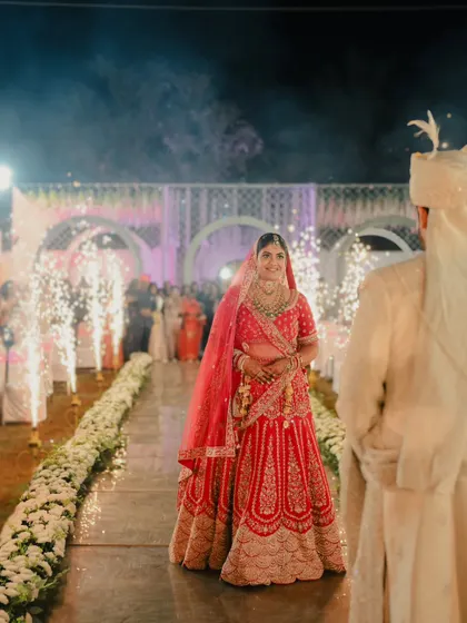 The bride's grand entrance. The groom watches as his bride walks down an aisle lined with flowers and cold pyro fireworks.