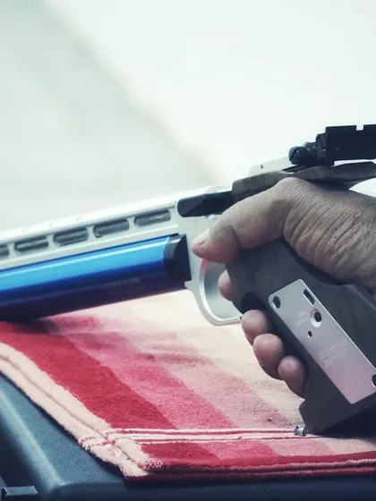A shooter's hand firmly gripping a competition air pistol. The ergonomic design of the equipment is crucial for stability and accurate shooting.