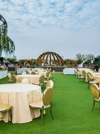 A wide shot of the rooftop lawn seating area, with a beautiful domed mandap in the background, ready for a grand wedding ceremony.
