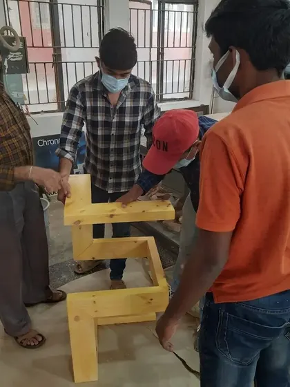 Our chief trainer provides guidance to students as they work on the assembly of a geometric table, ensuring every joint is perfect.
